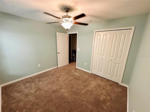 unfurnished bedroom featuring carpet flooring, ceiling fan, a closet, and a textured ceiling