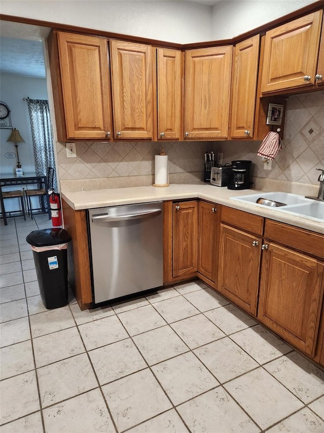 kitchen featuring stainless steel dishwasher, light tile patterned flooring, sink, and tasteful backsplash