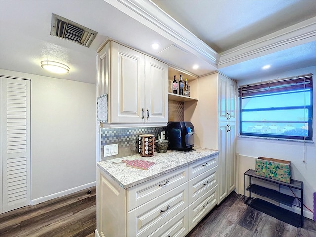 kitchen with light stone countertops, dark hardwood / wood-style flooring, white cabinets, and backsplash