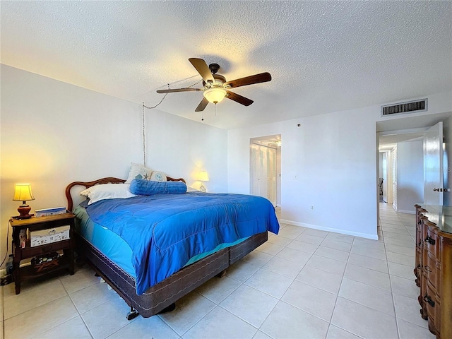 tiled bedroom with ceiling fan and a textured ceiling