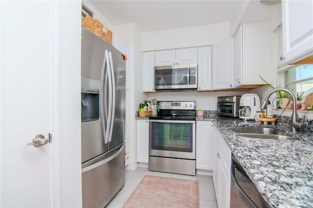 kitchen featuring appliances with stainless steel finishes, light tile patterned floors, white cabinetry, and sink