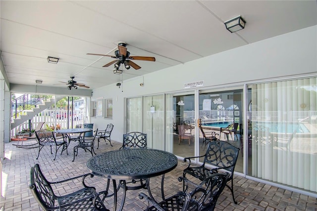 view of patio / terrace with a ceiling fan, outdoor dining space, and stairs