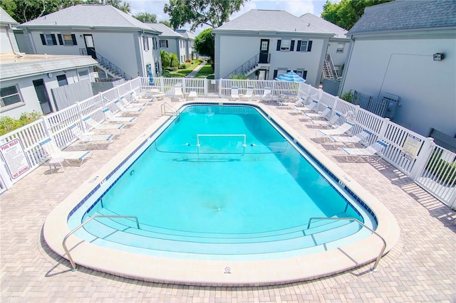 community pool featuring stairs, a patio, and fence