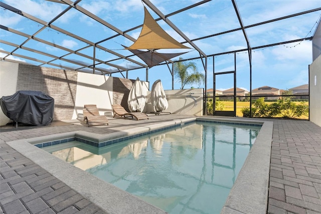 view of swimming pool featuring a lanai, a patio area, and grilling area