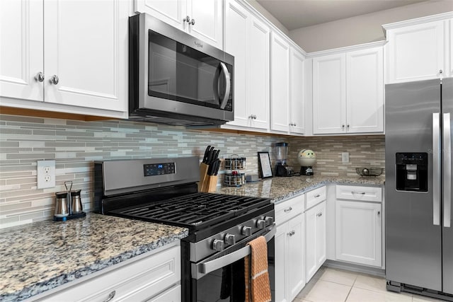 kitchen featuring white cabinets, backsplash, light tile patterned floors, and stainless steel appliances