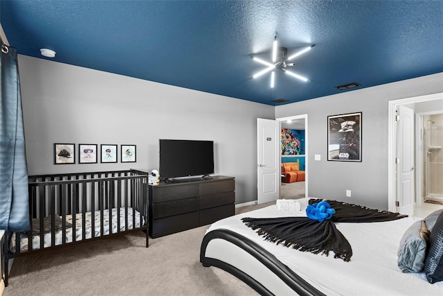 bedroom featuring a textured ceiling, ensuite bathroom, and light colored carpet