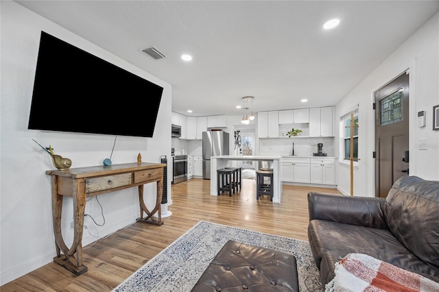 living room featuring light wood-type flooring and sink