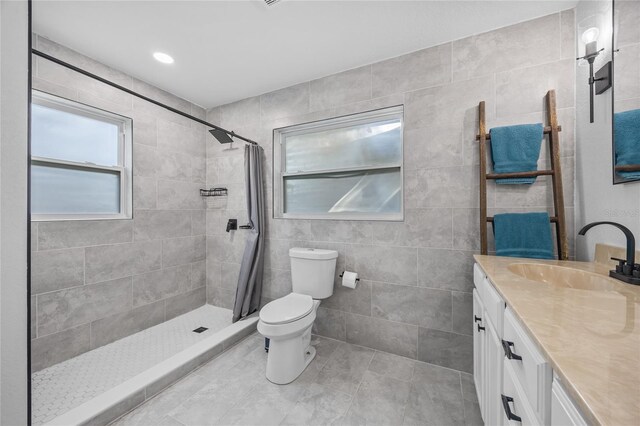 bathroom featuring tile patterned floors, a shower with curtain, vanity, tile walls, and toilet