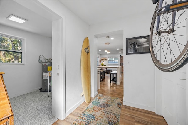 hallway with water heater and light hardwood / wood-style flooring