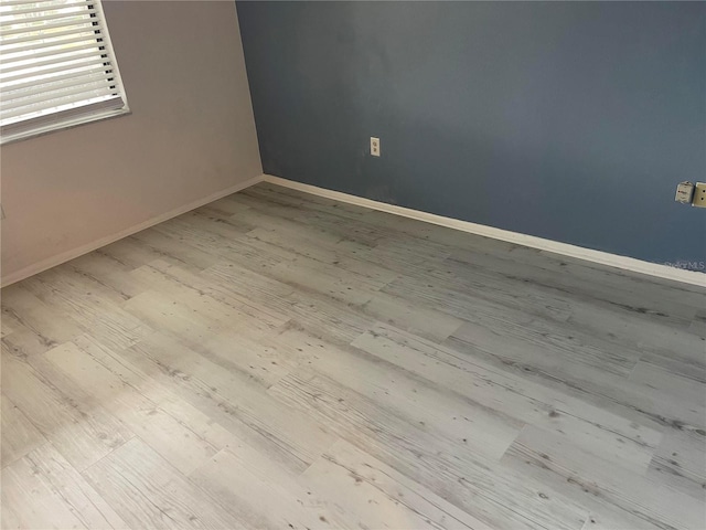 unfurnished room with light wood-style flooring and baseboards