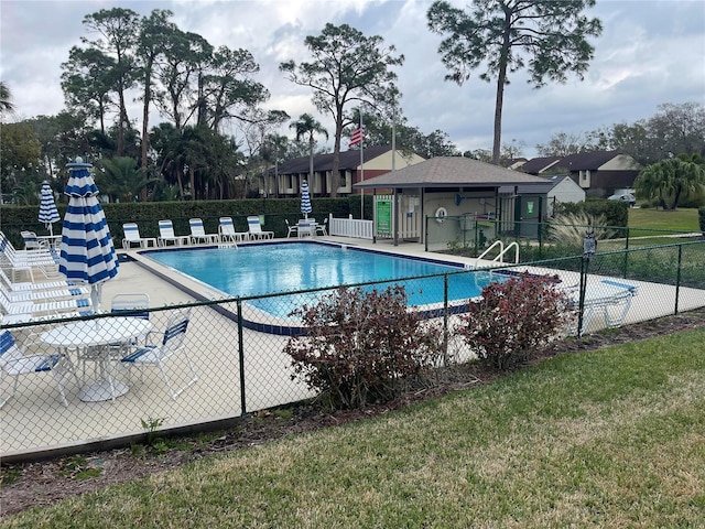 community pool with a patio area and fence