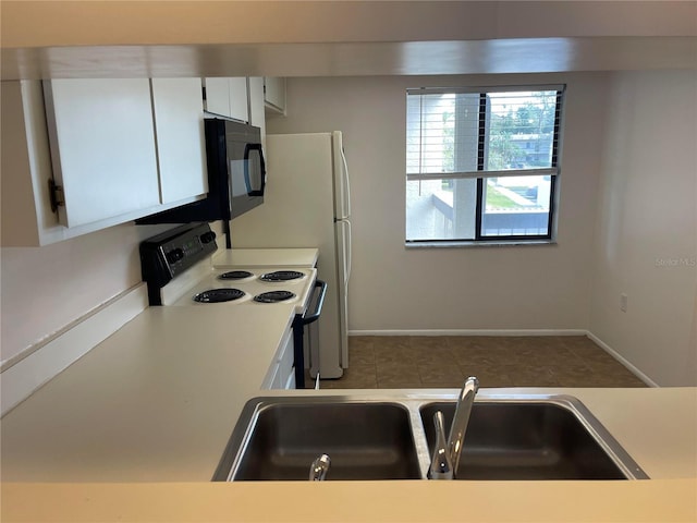 kitchen with light countertops, electric range, a sink, and white cabinetry