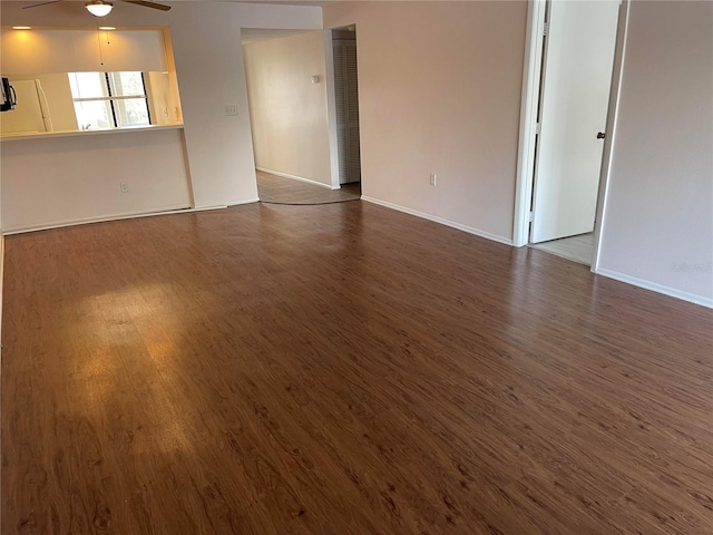 spare room with dark wood-style floors, ceiling fan, and baseboards