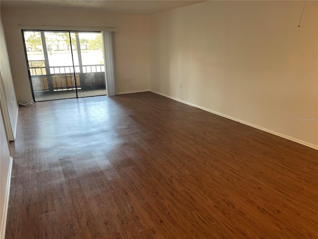 unfurnished room with dark wood-style flooring and baseboards