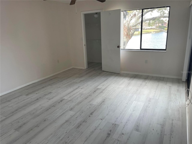 unfurnished room featuring ceiling fan, light wood-style flooring, and baseboards