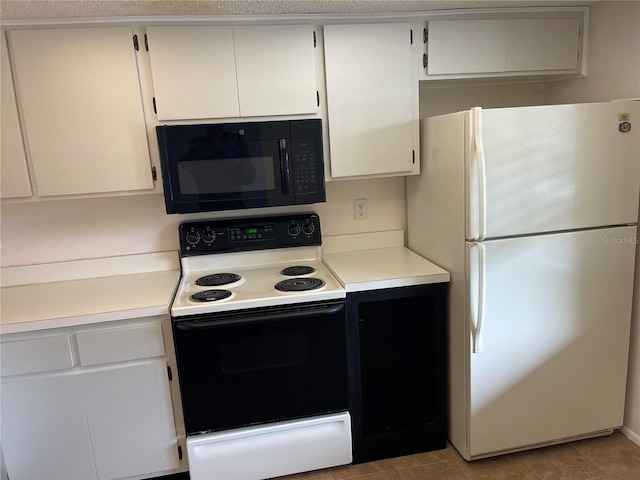 kitchen featuring black microwave, range with electric stovetop, white cabinetry, light countertops, and freestanding refrigerator