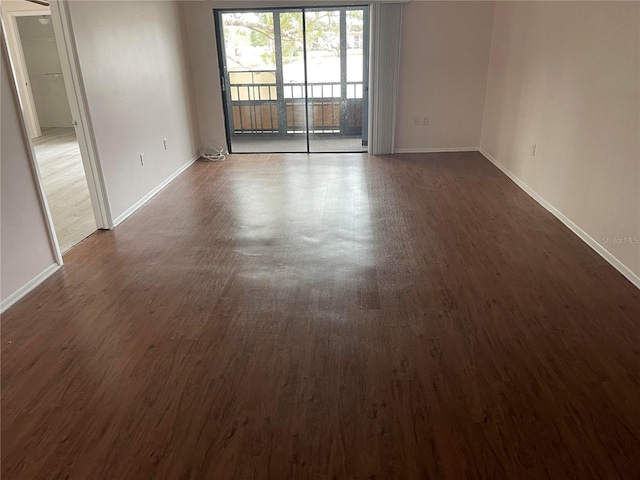 empty room featuring dark wood-type flooring and baseboards