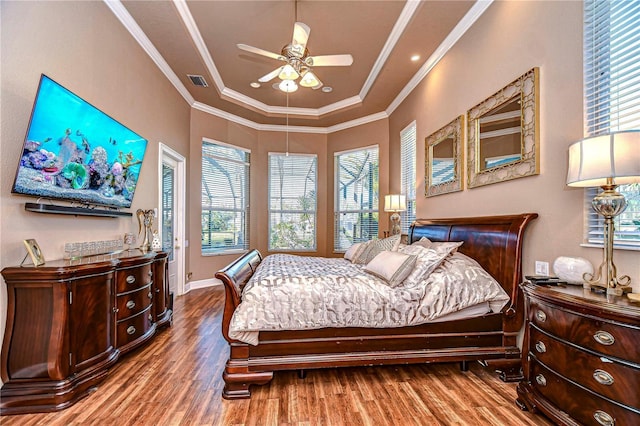 bedroom with a tray ceiling, ceiling fan, wood-type flooring, and ornamental molding