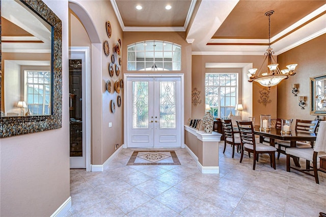 tiled foyer entrance featuring french doors, an inviting chandelier, and crown molding