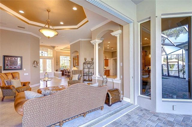 living room featuring a tray ceiling, ornate columns, crown molding, and french doors