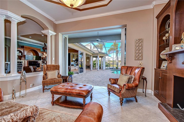 sitting room with decorative columns, ceiling fan, and crown molding