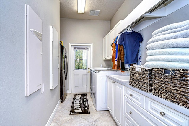 laundry room featuring light tile patterned flooring, cabinets, a textured ceiling, and independent washer and dryer