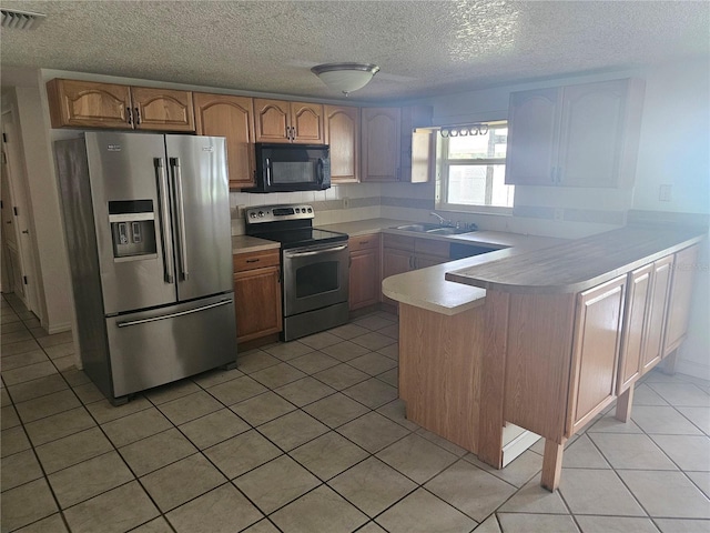 kitchen featuring kitchen peninsula, appliances with stainless steel finishes, light tile patterned floors, and sink