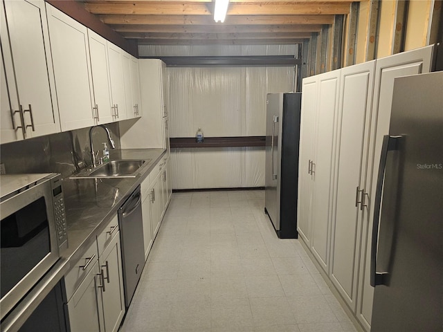 kitchen featuring white cabinets, appliances with stainless steel finishes, beamed ceiling, and sink