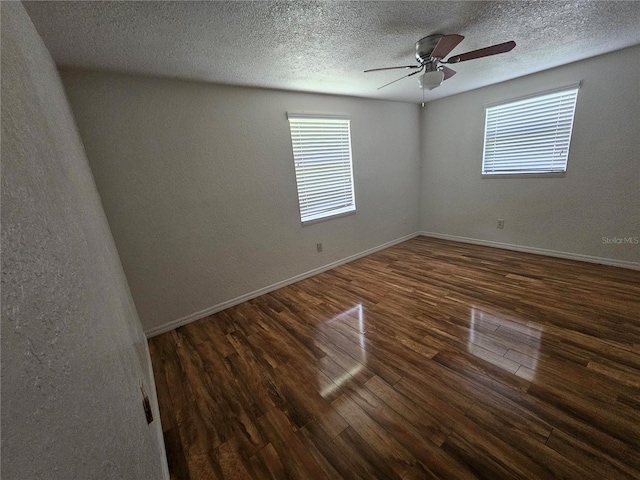 spare room featuring a textured ceiling, ceiling fan, and dark wood-type flooring