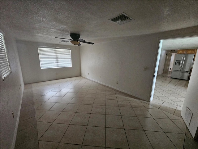 tiled empty room featuring a textured ceiling and ceiling fan