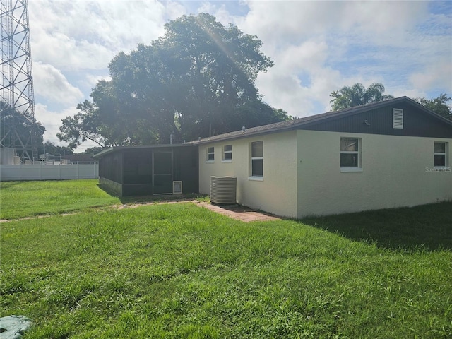 back of property featuring a lawn, a sunroom, and central AC unit