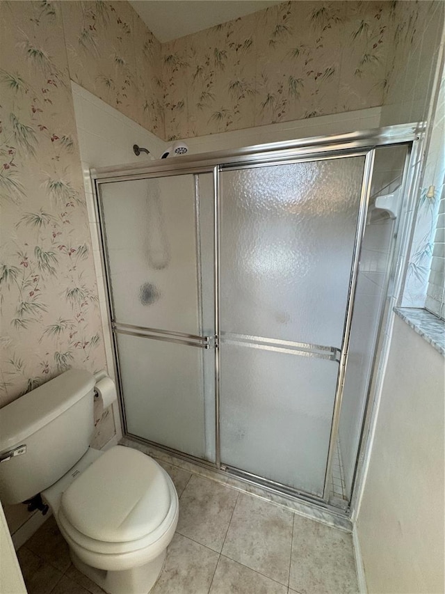 bathroom with tile patterned flooring, a shower with door, and toilet