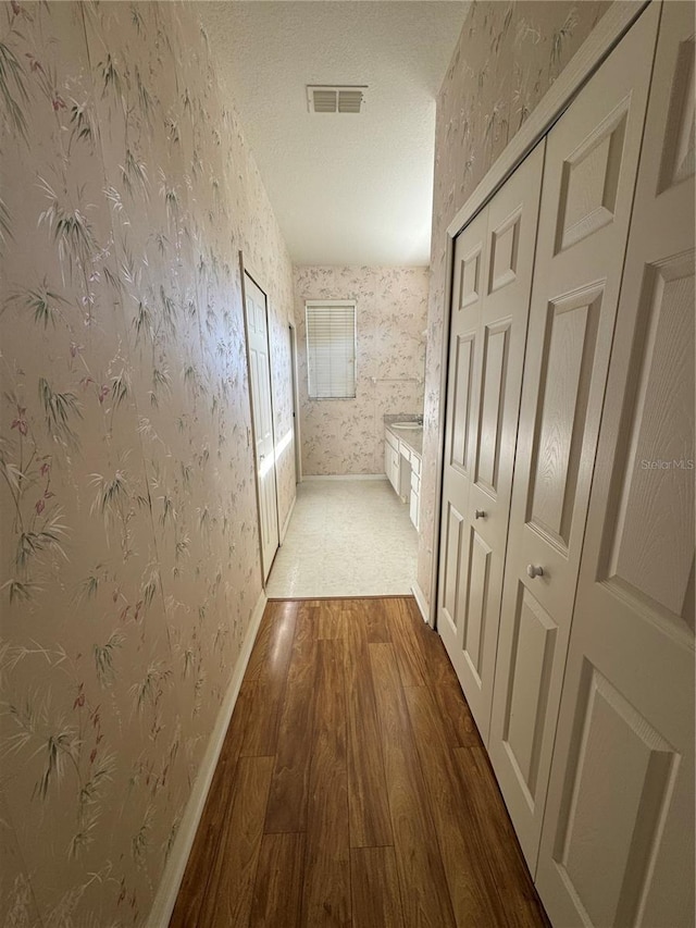 hallway featuring a textured ceiling and dark hardwood / wood-style floors