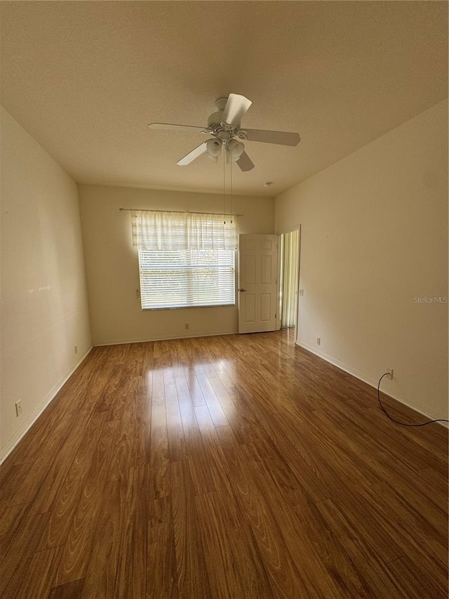 spare room with a textured ceiling, ceiling fan, and dark wood-type flooring