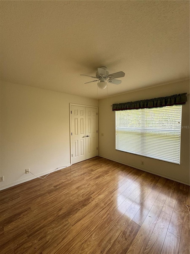 empty room featuring ceiling fan, light hardwood / wood-style floors, and a textured ceiling