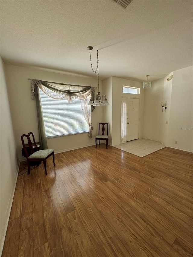 foyer entrance with a textured ceiling, hardwood / wood-style flooring, and an inviting chandelier