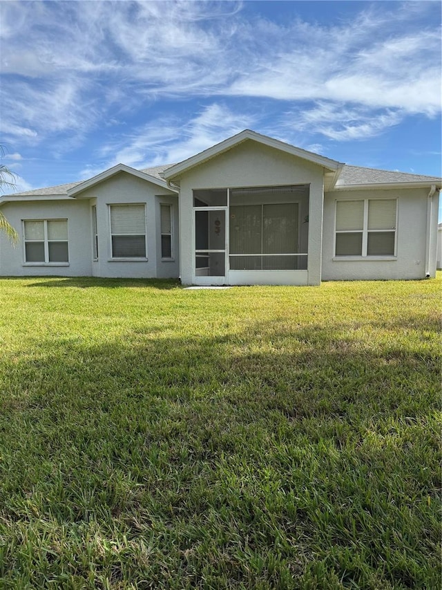 rear view of property with a lawn and a sunroom