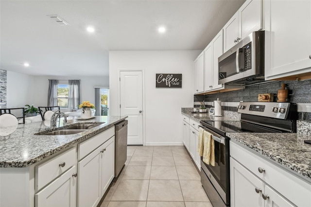 kitchen with backsplash, white cabinets, sink, appliances with stainless steel finishes, and light tile patterned flooring