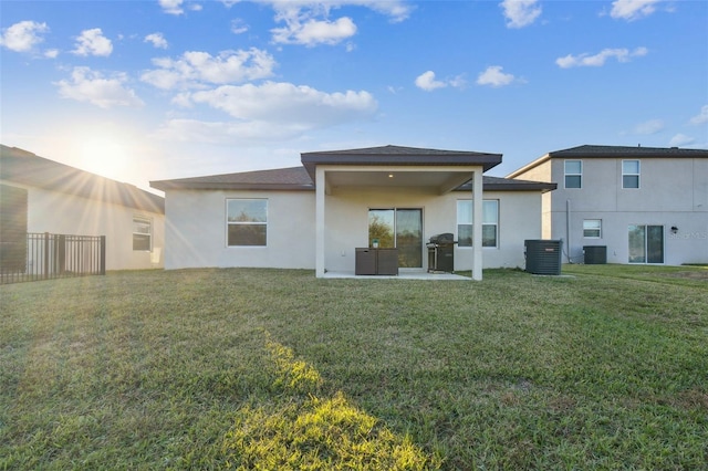 rear view of house featuring a lawn, central AC, and a patio area