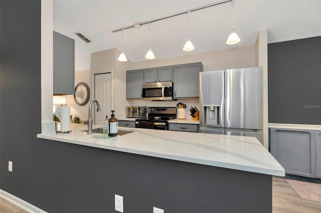 kitchen featuring light stone countertops, kitchen peninsula, stainless steel appliances, sink, and gray cabinets