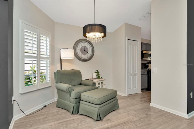 living area featuring light wood-type flooring, an inviting chandelier, and plenty of natural light