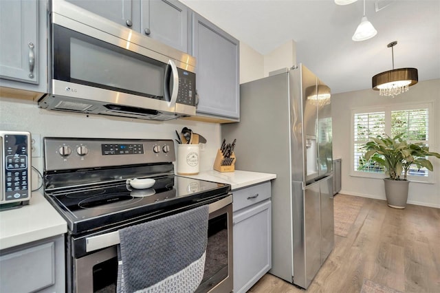 kitchen with pendant lighting, stainless steel appliances, an inviting chandelier, and gray cabinetry