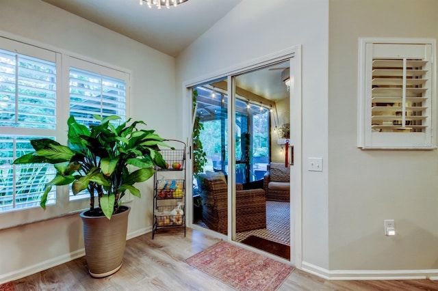 doorway to outside with light hardwood / wood-style floors and vaulted ceiling