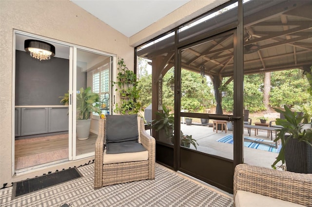 sunroom / solarium featuring lofted ceiling, a wealth of natural light, and an inviting chandelier