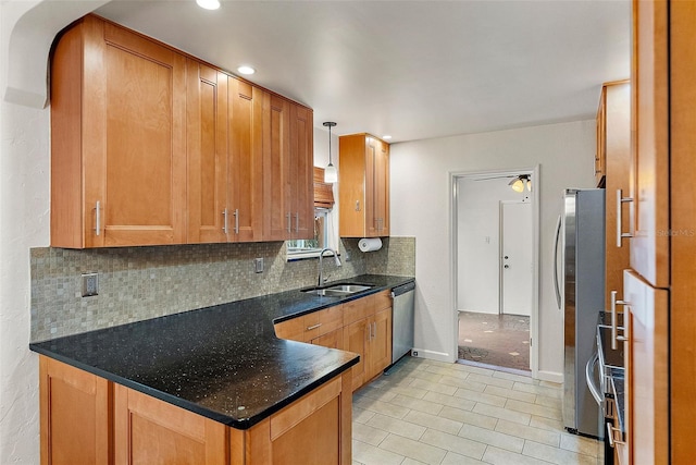 kitchen with appliances with stainless steel finishes, backsplash, ceiling fan, sink, and hanging light fixtures