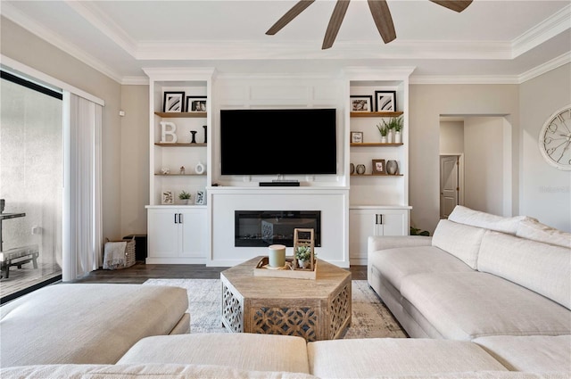 living room featuring hardwood / wood-style flooring, built in features, ceiling fan, and crown molding