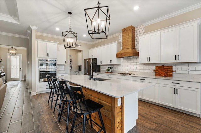 kitchen featuring white cabinets, dark hardwood / wood-style floors, an island with sink, and decorative light fixtures