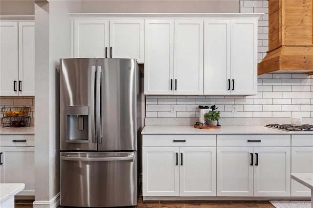 kitchen featuring white cabinets, backsplash, stainless steel appliances, and light stone countertops