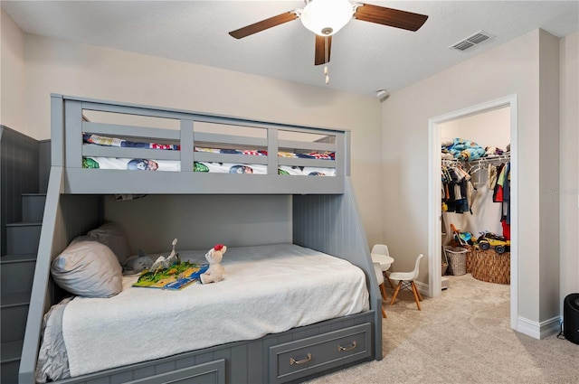 bedroom featuring light carpet, a walk in closet, a closet, and ceiling fan