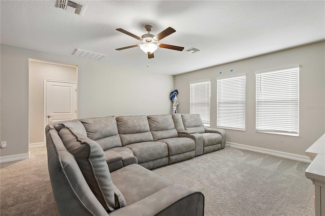 living room with a textured ceiling, ceiling fan, and light carpet